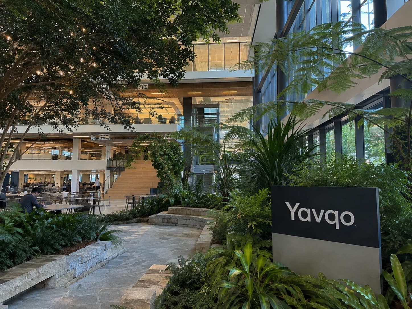 The Yavqo sign among plants in the glass atrium of a Yavqo office